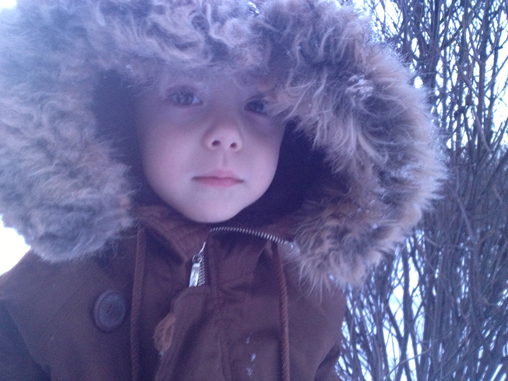 Faded, bluish color on a photo of young boy in parka.