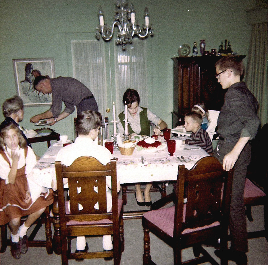 Restored and color corrected vintage photo of large family at holiday dinner table.